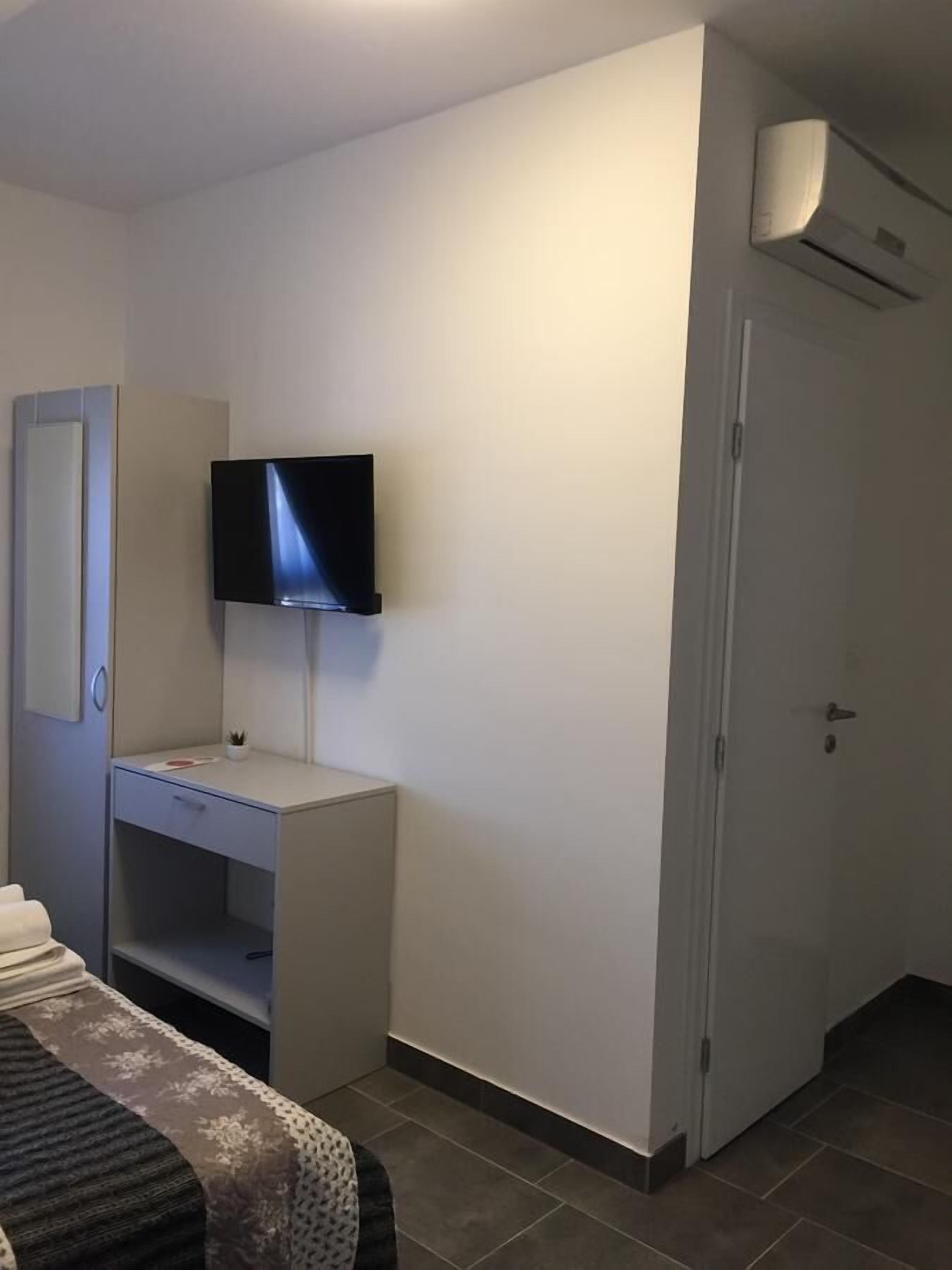 Una habitación de hotel con cama, escritorio, televisor y aire acondicionado.
