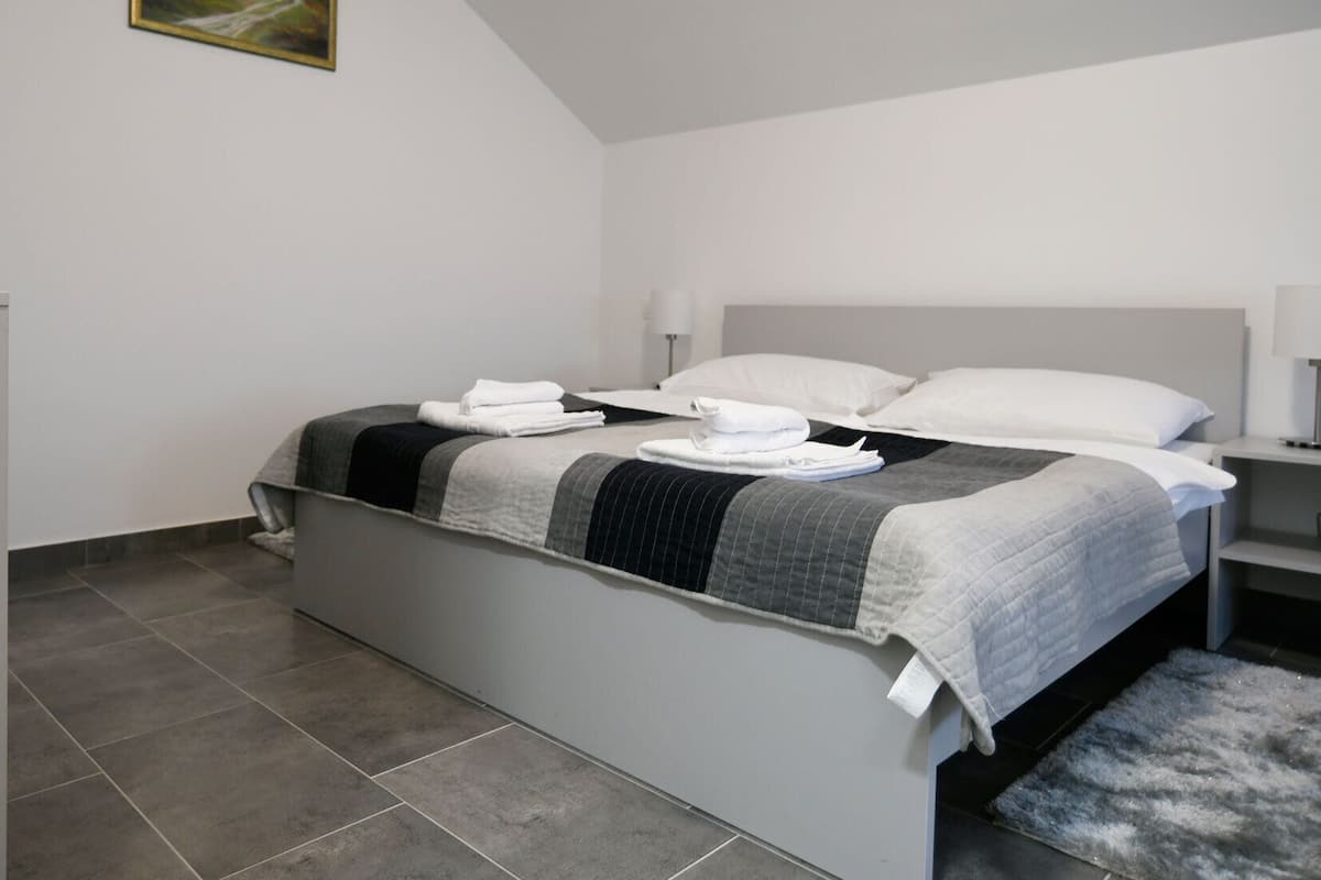 A modern bedroom with a bed, bedside tables, and a rug.