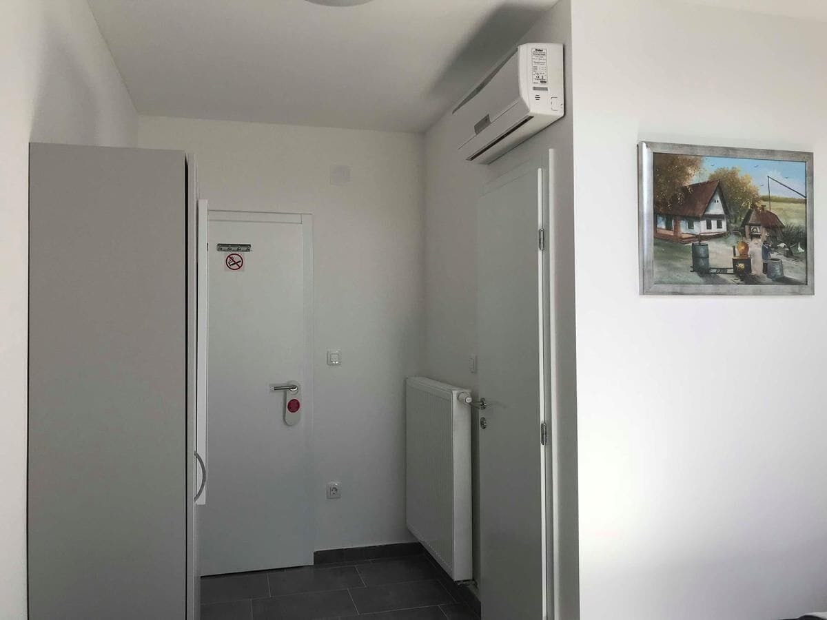 A narrow hallway with a closed door, a radiator, and an air conditioning unit mounted on the wall.