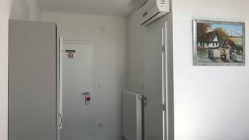 A narrow hallway with a closed door, a radiator, and an air conditioning unit mounted on the wall.