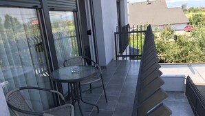 A balcony with a glass door, a round table, and two wicker chairs.