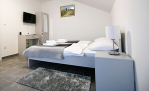 A modern bedroom with a bed, bedside table, lamp, TV, and a painting on the wall.