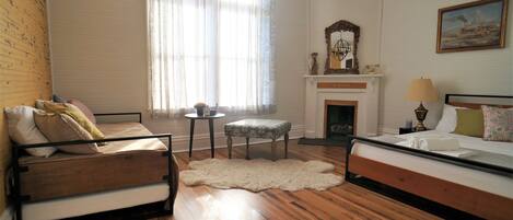 Una habitación con una cama, un sofá, una mesita, una silla, una chimenea y un candelabro.