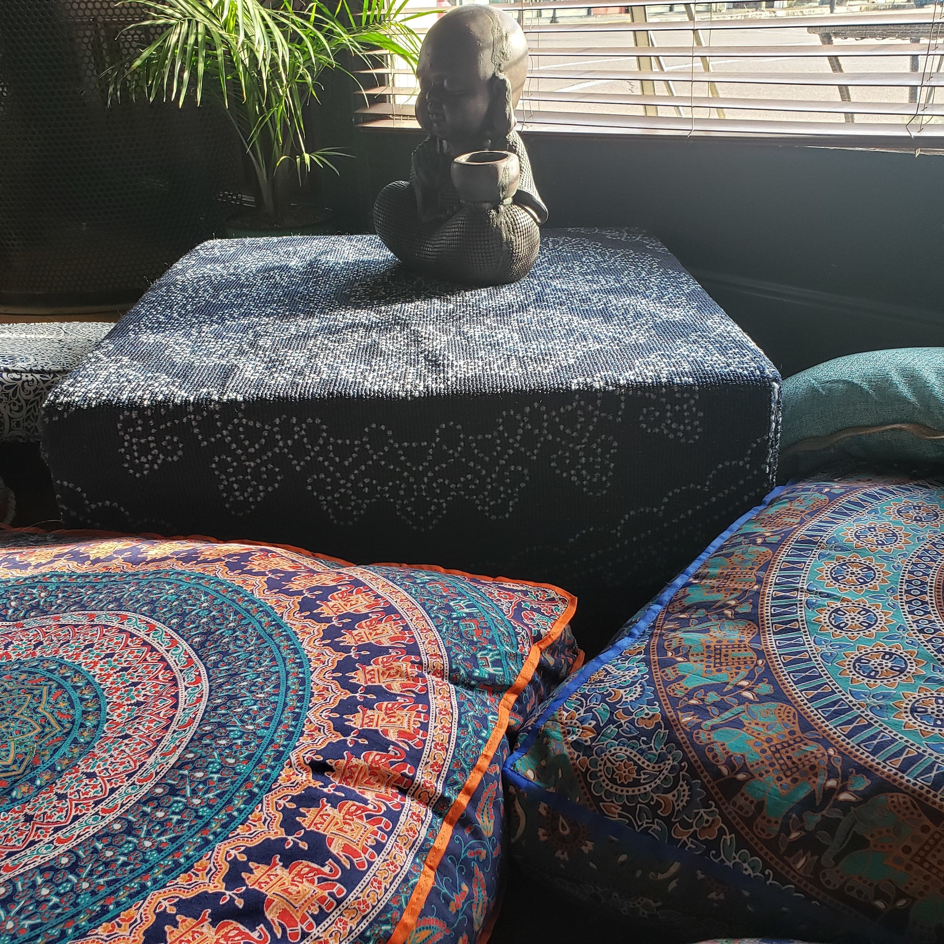Una habitación con un reposapiés estampado y una estatua decorativa.