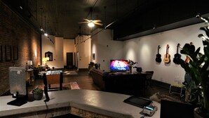 Un área de estar moderna con un televisor de pantalla plana, ventiladores de techo y guitarras en la pared.