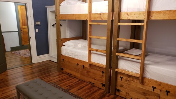 A bunk bed room with a bench and a door.