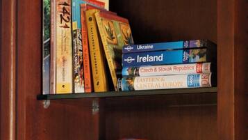 A wooden shelf with a Road Atlas, travel guides, a camera, and wine glasses.