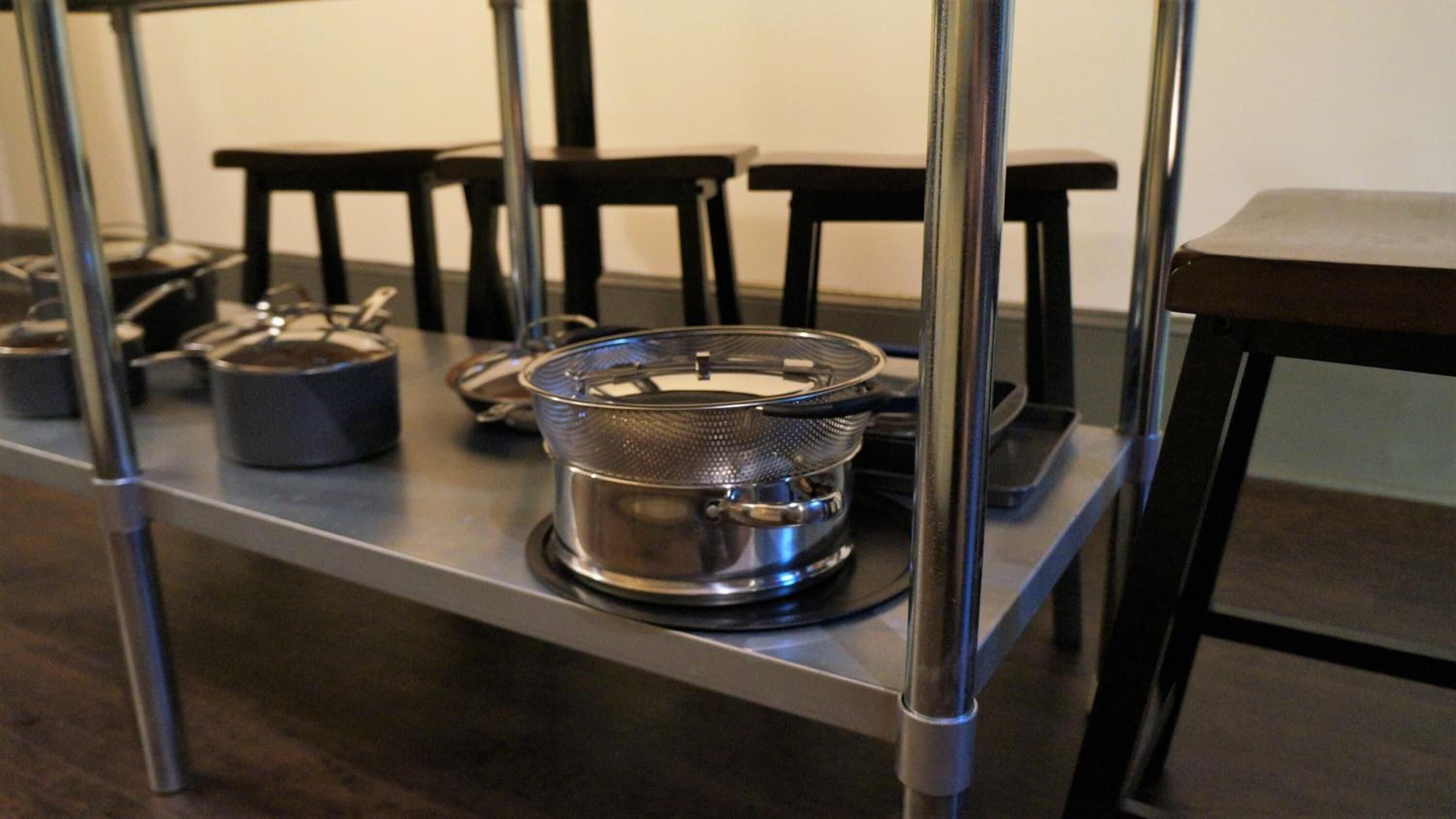A kitchen area with stainless steel appliances, including a kettle and a pot on a shelf.