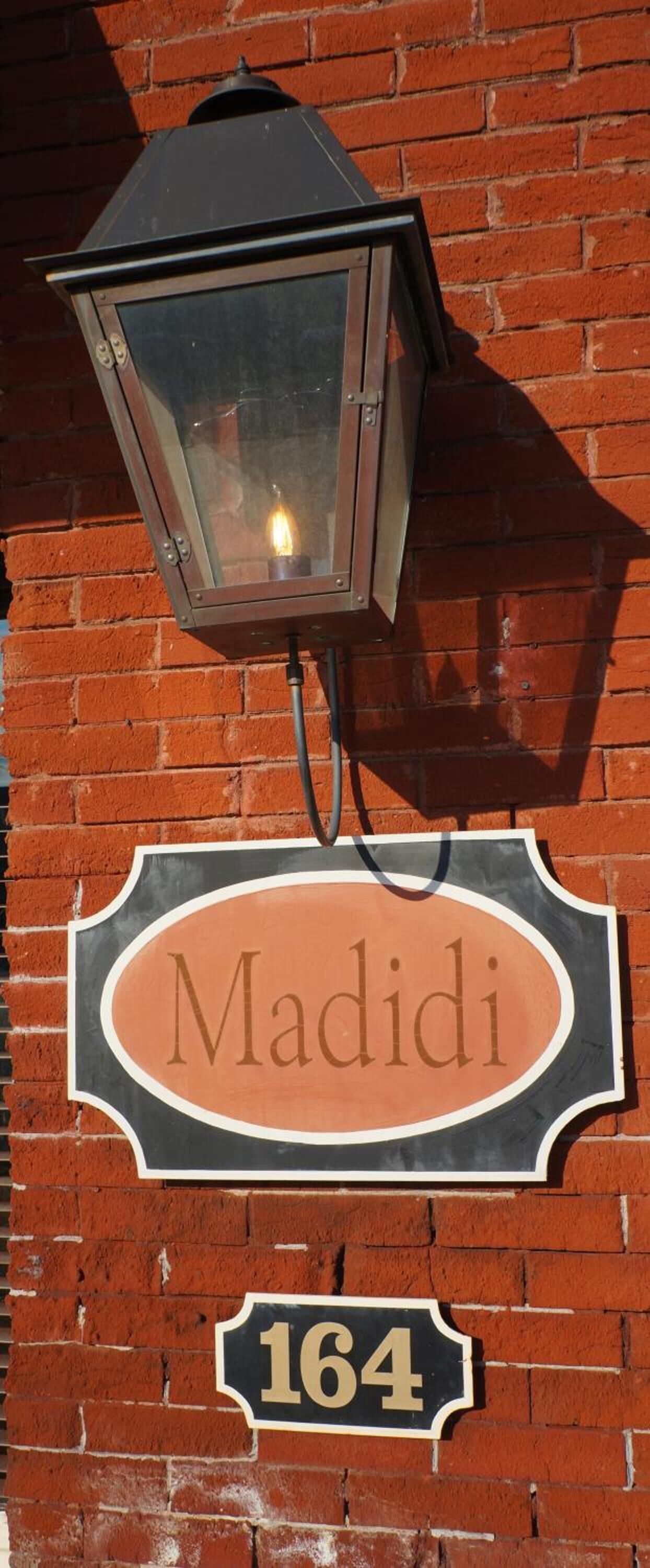 Eine Ziegelwand mit einem Straßenschild, auf dem "Madidi" und die Nummer "164" stehen.