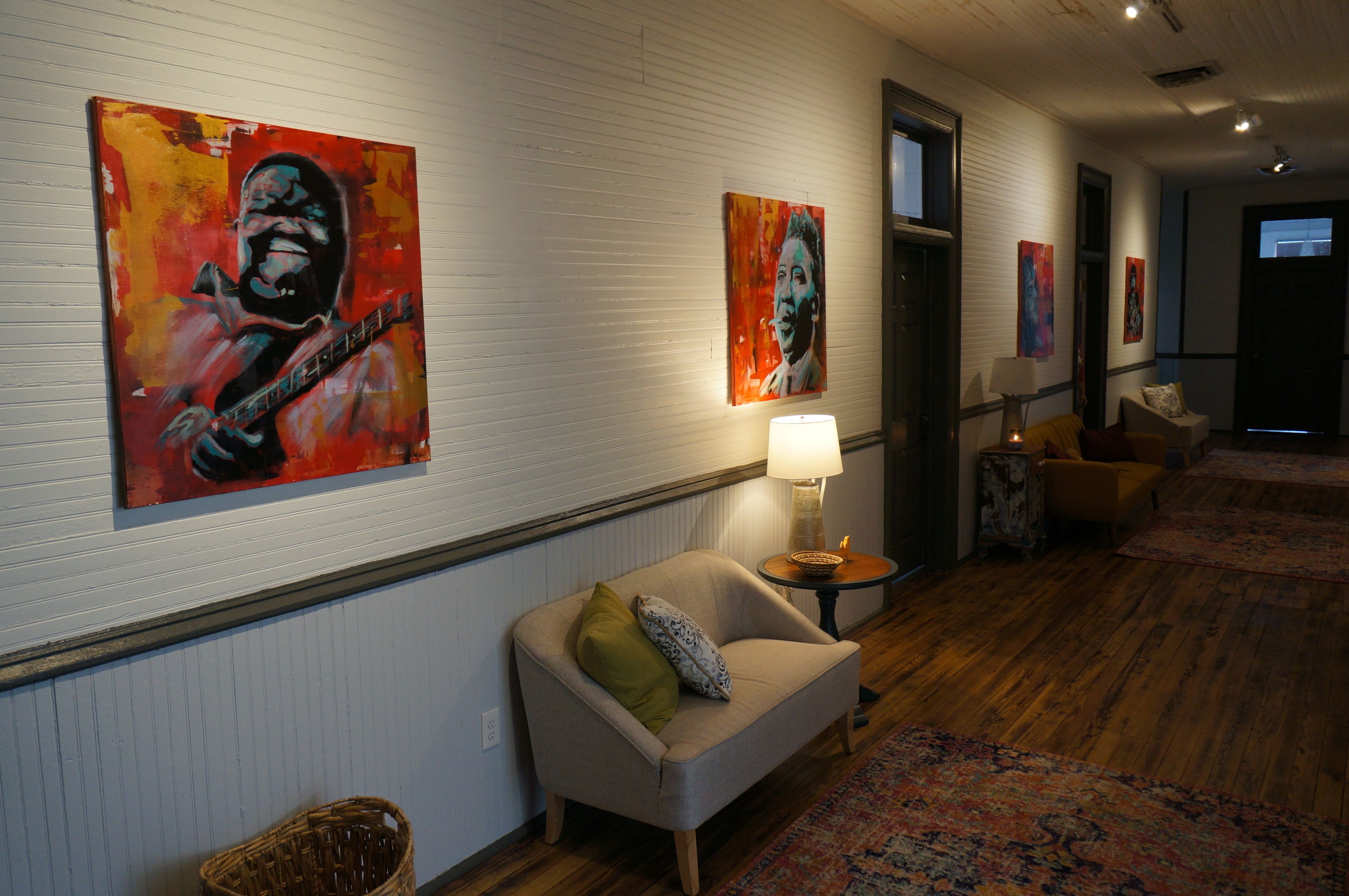 A hallway with a sofa, a lamp, and artwork on the walls.
