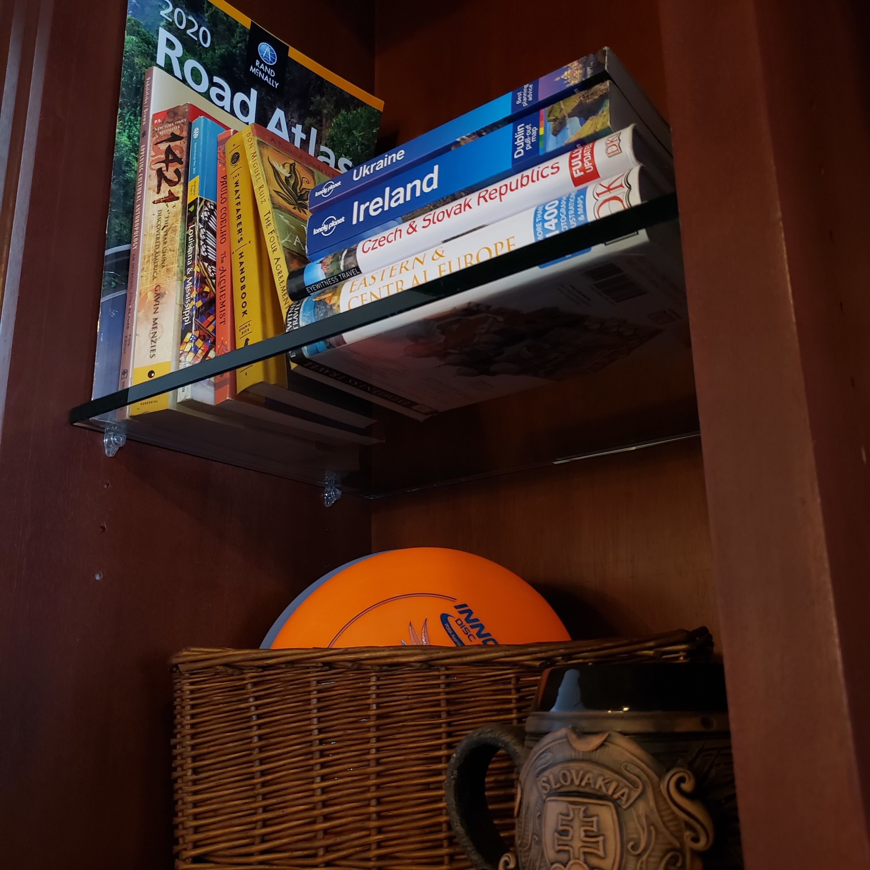 A bookshelf with travel books and a globe.