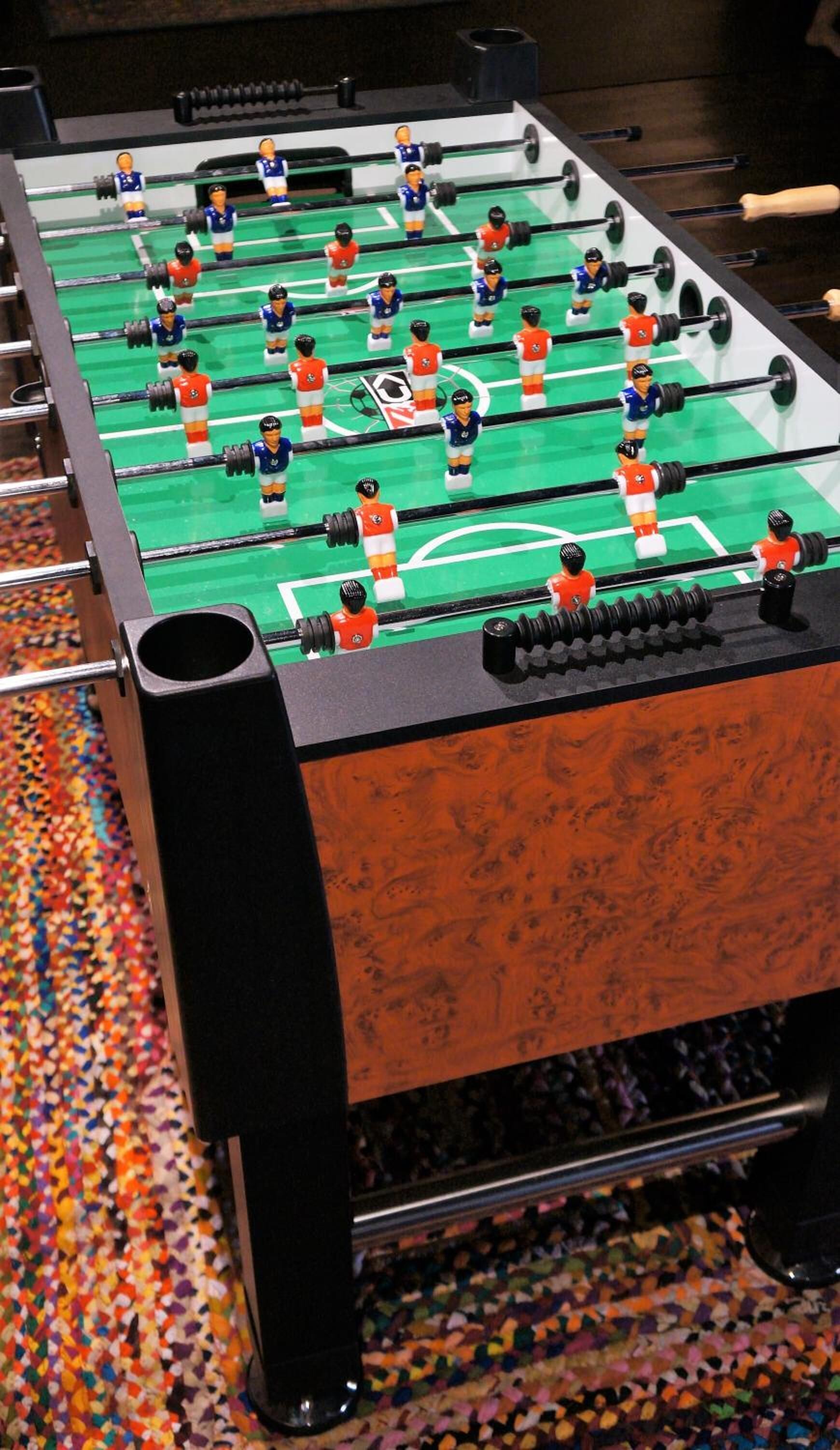 Ein Kicker mit mehreren Spielern und einem bunten, farbenfrohen Teppich.