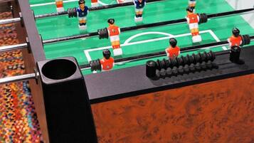 Ein Kicker mit mehreren Spielern und einem bunten, farbenfrohen Teppich.