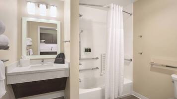 A modern bathroom with a sink, mirror, and shower area.