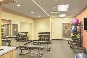 Une salle de sport équipée de matériel de musculation, de ballons d’exercice et d’haltères.