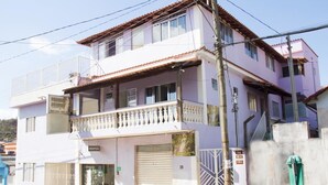 Un edificio de dos pisos con un balcón en el segundo nivel, una puerta de garaje y una entrada con reja.
