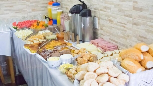Una mesa de buffet con diversos alimentos, entre ellos frutas, quesos, carnes y pan.