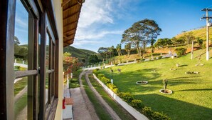Vista dall'interno di un edificio su un prato curato, con un vialetto che conduce a una collina.