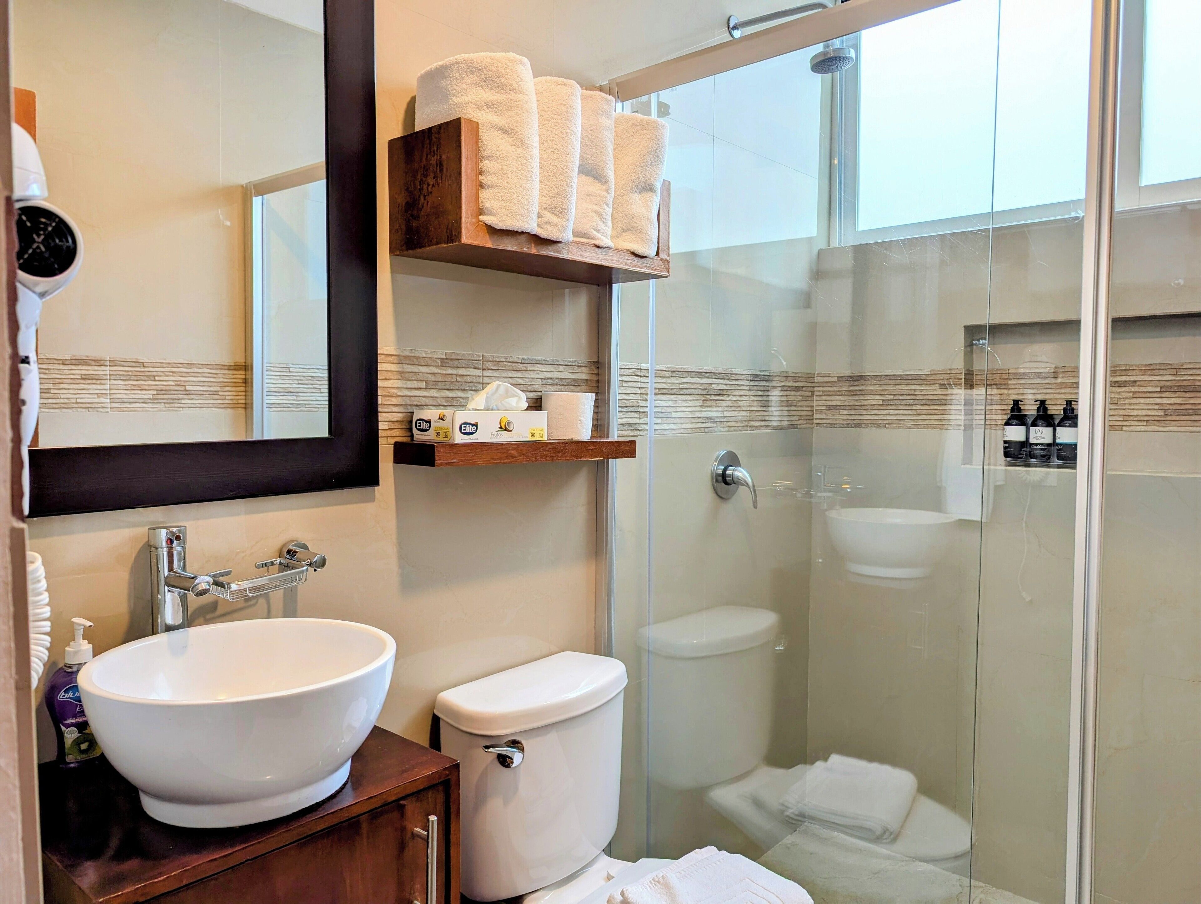 A modern bathroom with a large white sink, a toilet, and a glass-enclosed shower.