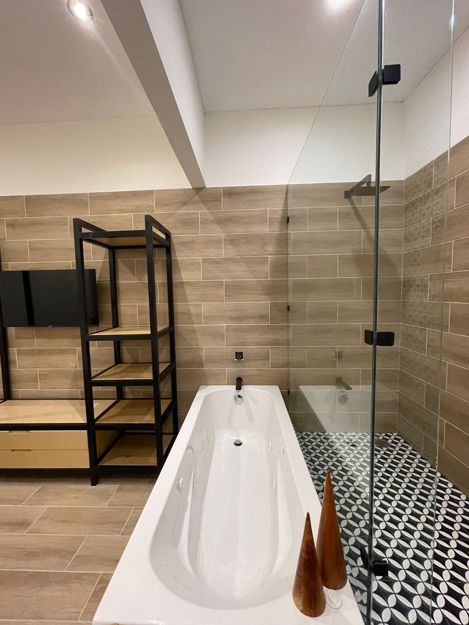 Un baño moderno con una bañera independiente, una ducha con cerramiento de vidrio y un piso con diseño blanco y negro.