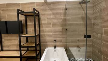 Un baño moderno con una bañera independiente, una ducha con cerramiento de vidrio y un piso con diseño blanco y negro.
