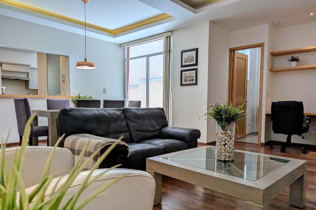 Una sala de estar moderna con un sofá de cuero, una mesa de centro de vidrio y un comedor con una mesa y sillas.