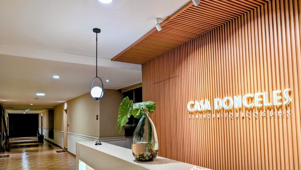 A reception desk with a wooden panel wall and a sign reading "CASA DONCELES CENTRO HISTORICO CDMX". - Casa Donceles Apartments & Suites, Alojamientos ideales para familias y grupos (Mexico City)