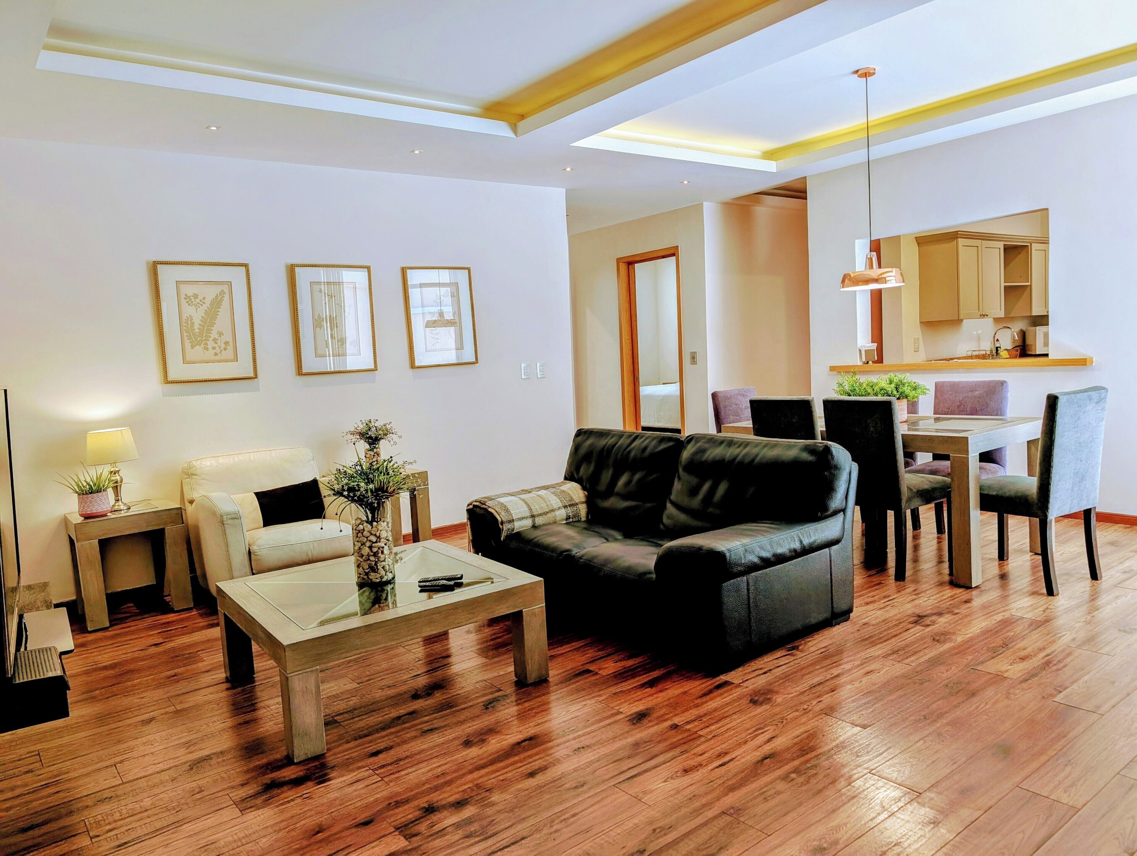 Una sala moderna con sofá, mesa de centro y comedor con sillas y mesa.