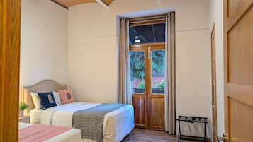 Un dormitorio con una cama, una mesita de noche, un ventilador de techo, una ventana con cortinas y una puerta.