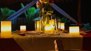 A table set for a romantic dinner with candles, glasses, and a vase of flowers. - Hotel Villa Murano (Tonalá)