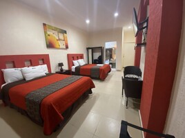 A hotel room with two beds, a desk, a chair, and a painting on the wall.