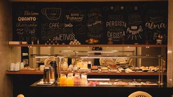 Un espace buffet pour le petit-déjeuner avec un mur noir où sont écrites différentes phrases inspirantes, ainsi qu’une machine à café.