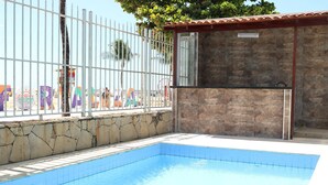 A swimming pool with a stone wall and a metal fence. - Sonho de Iracema Hostel Boutique (Fortaleza)