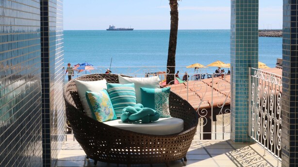 A balcony with a wicker chair, a view of the sea, and a ship in the distance. - Sonho de Iracema Hostel Boutique (Fortaleza)