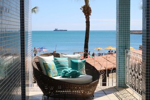 A balcony with a wicker chair, a view of the sea, and a ship in the distance. - Sonho de Iracema Hostel Boutique (Fortaleza)