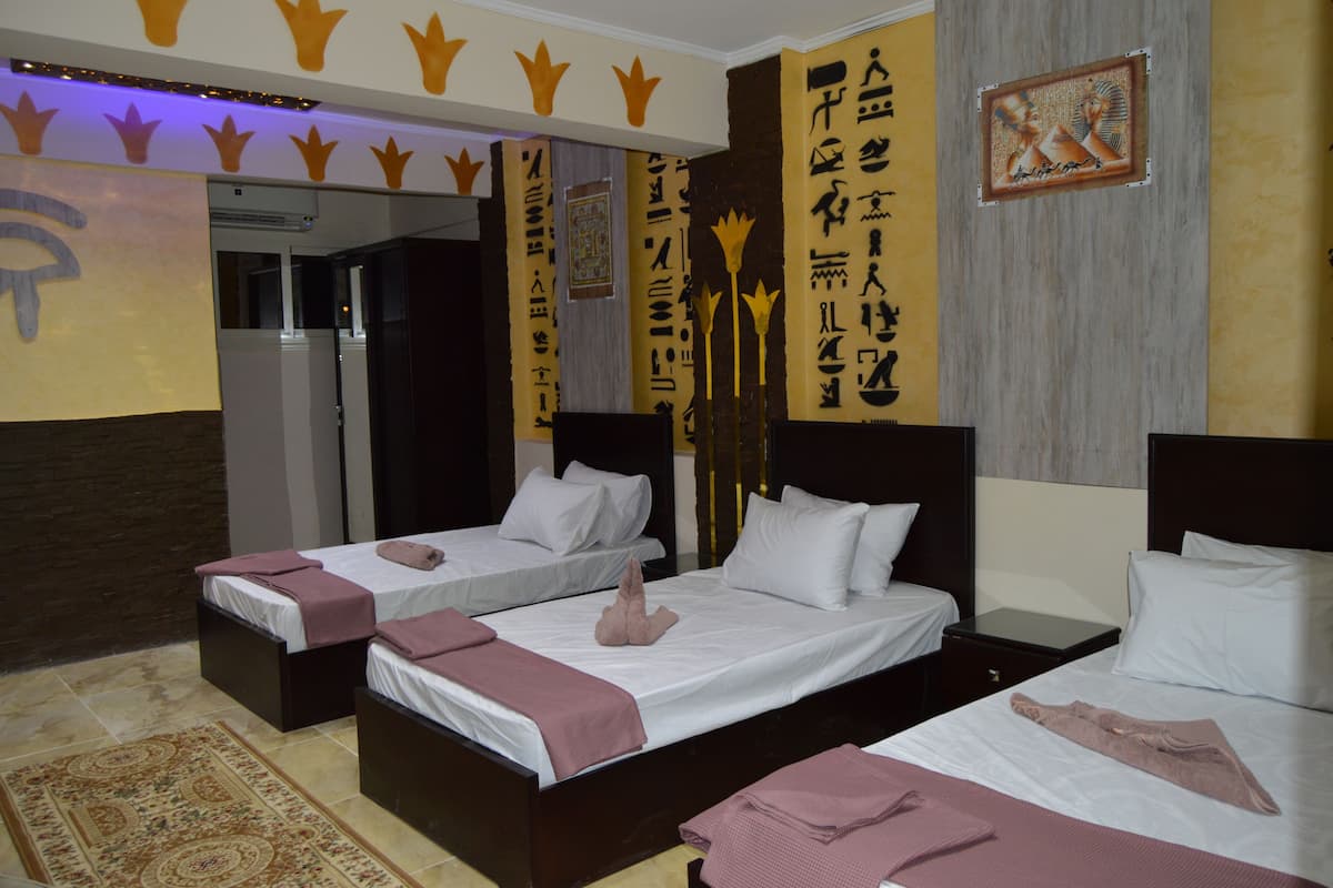 A hotel room with two single beds, a large window, and a wall with decorative elements.