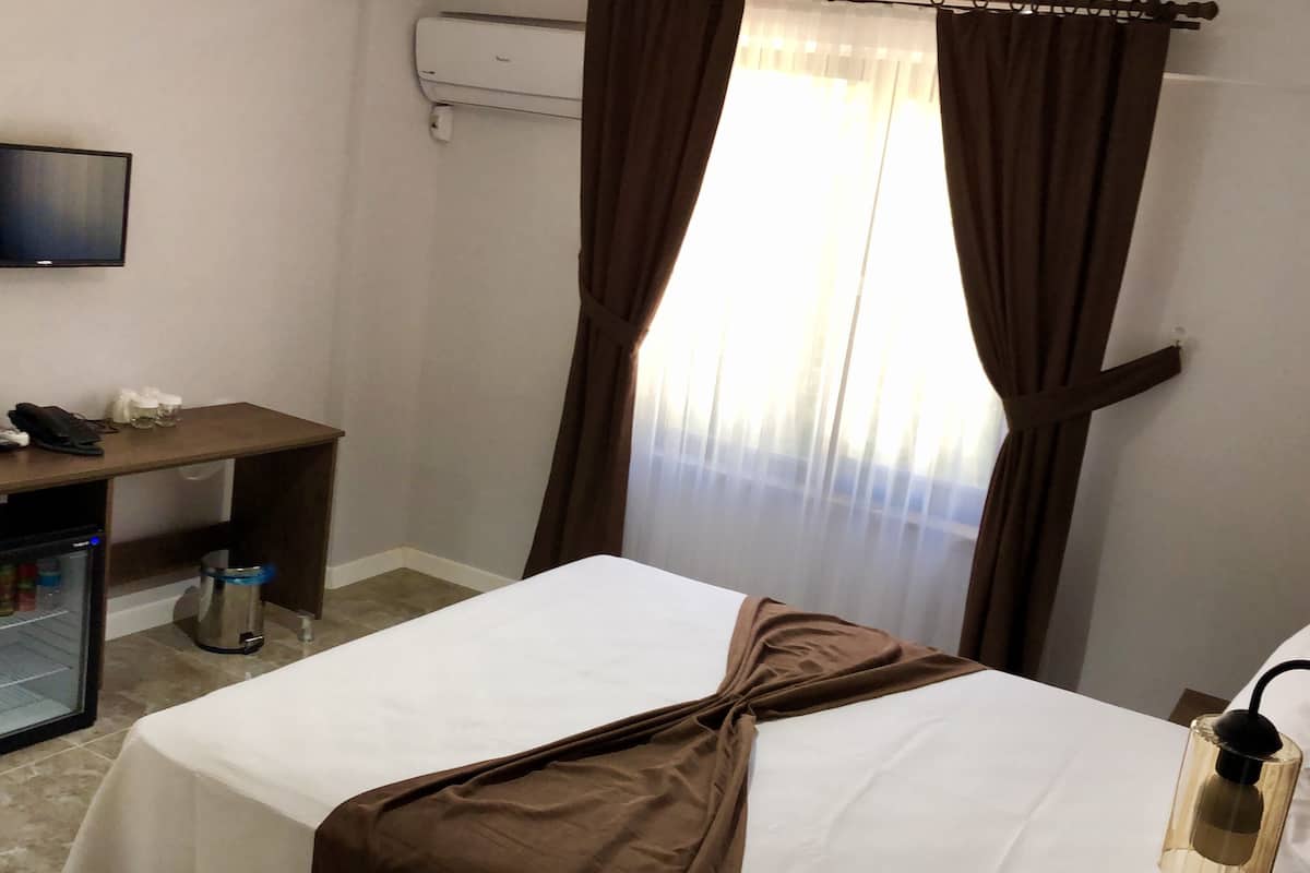 Une chambre d’hôtel équipée d’un lit, d’un bureau, d’une télévision et d’un mini-bar.