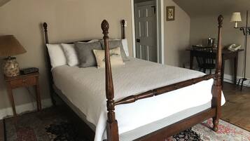 Un dormitorio con cama con dosel, una mesita de noche con lámpara, una silla y un escritorio con lámpara.