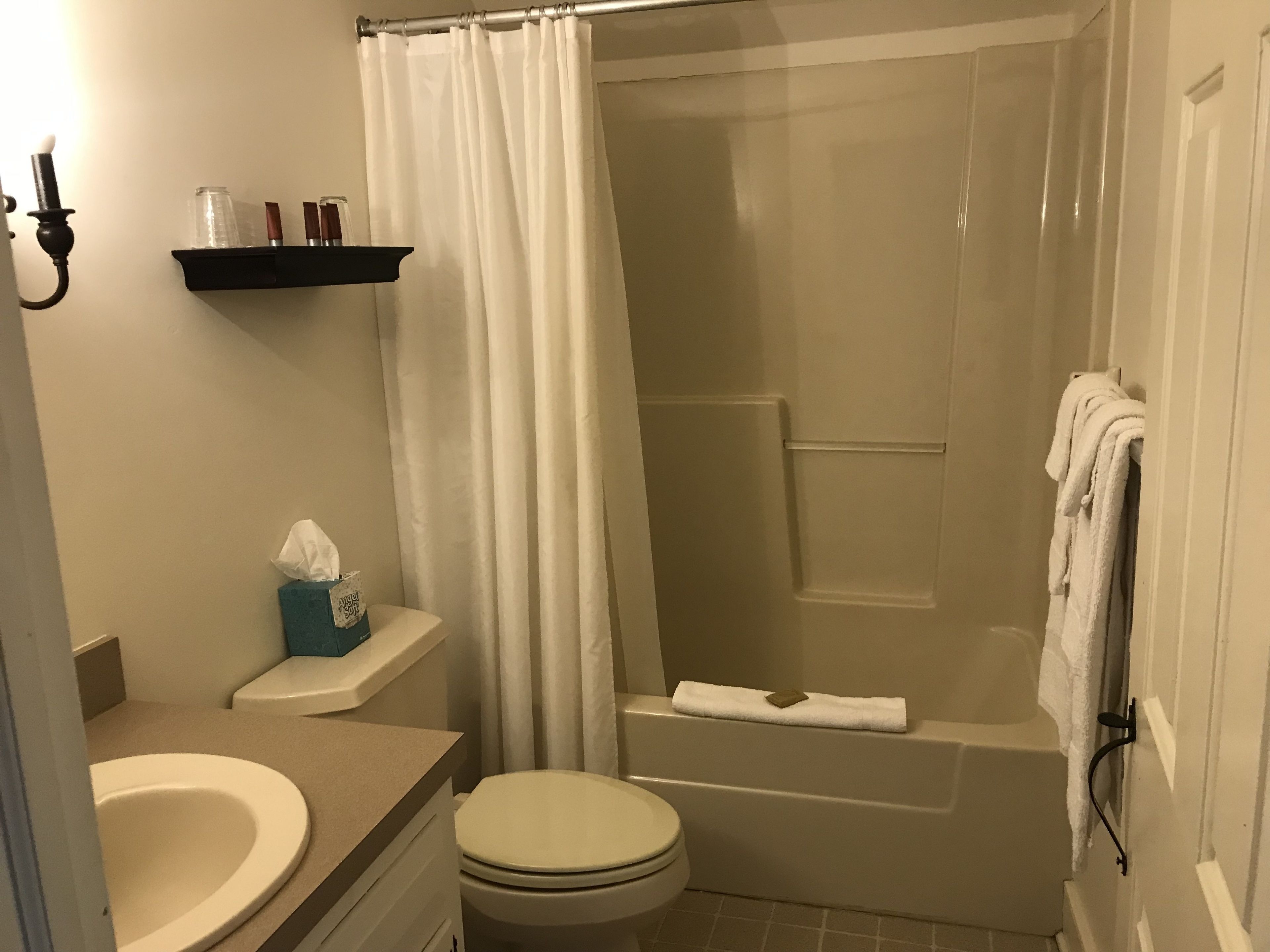 A bathroom with a toilet, sink, bathtub, and shower curtain.