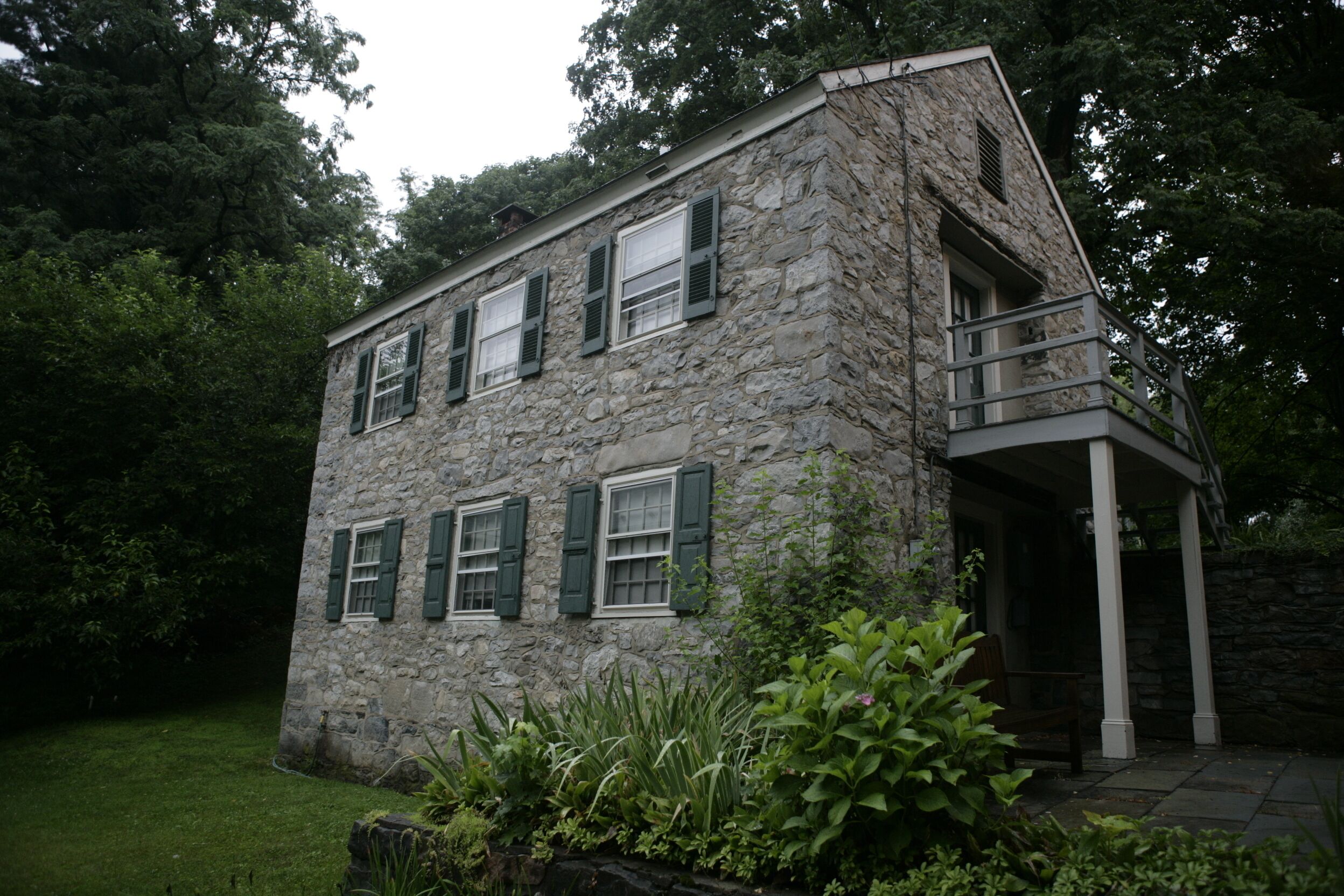 A stone building with a balcony and a covered porch.