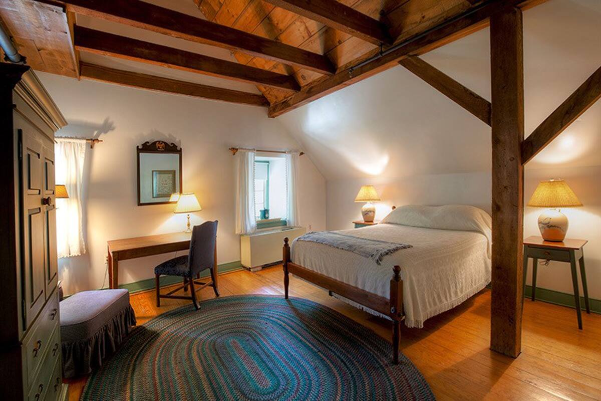 Un dormitorio con techo de madera, una cama, un escritorio y una silla.