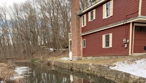A red building with a stone wall and a pond in front. - Inn at Millrace Pond (Blairstown)