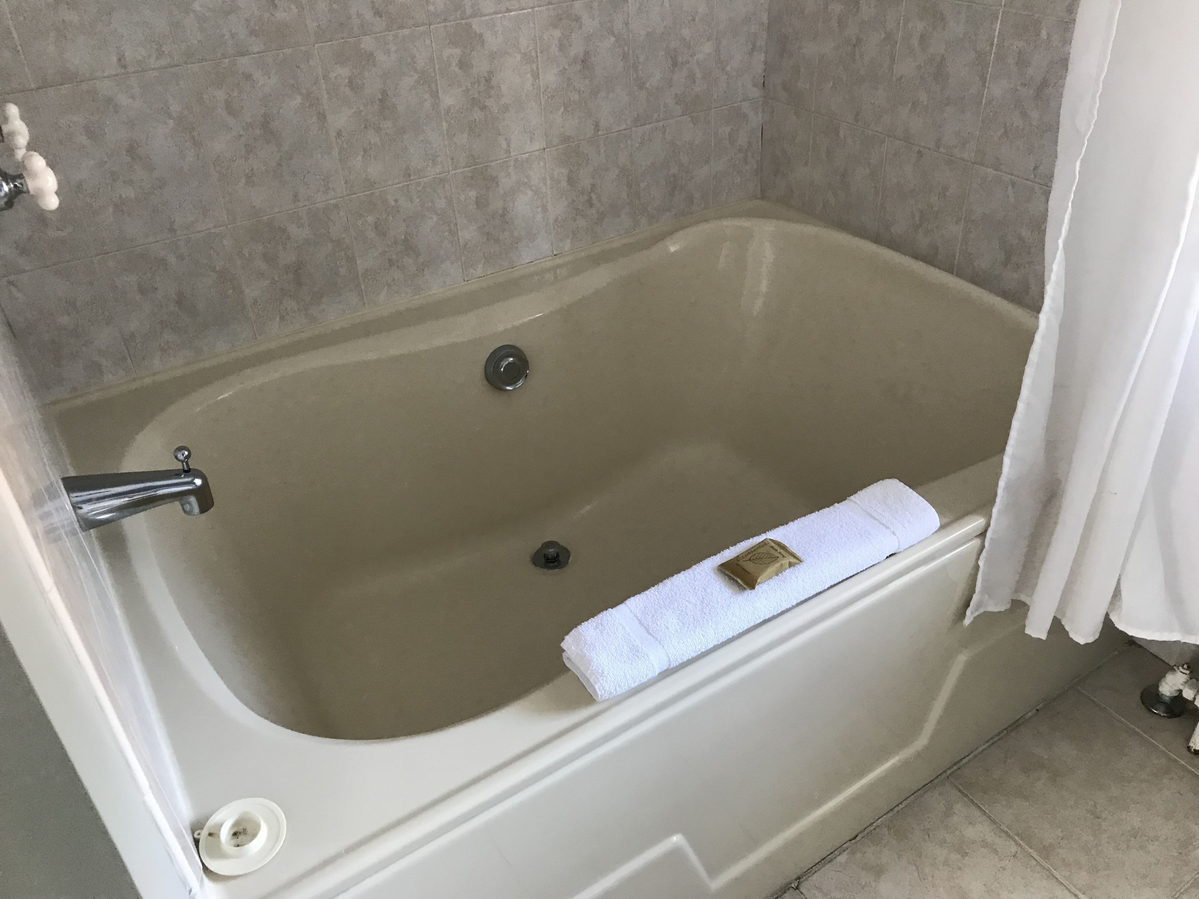 A bathtub with a white towel, a faucet, and a drain.