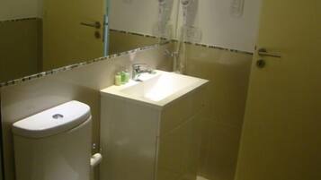 A small bathroom with a toilet, sink, and two towel racks above the mirror.