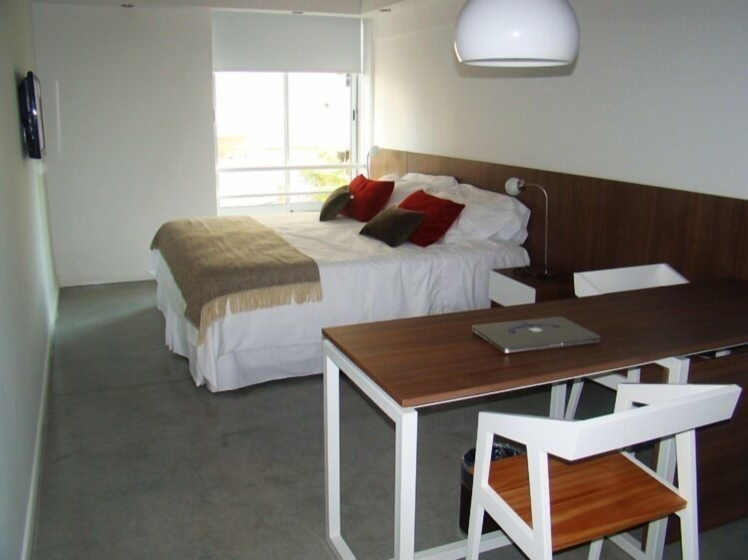 A bedroom with a bed, a desk, a chair, and a lamp.