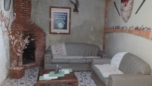 Ein Wohnzimmer mit Kamin aus Ziegelsteinen, einem grauen Sofa, einem Couchtisch mit grüner Unterlage und einem gerahmten Poster an der Wand.
