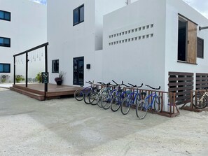 A modern building with a concrete ground floor, a wooden deck, and a row of bicycles parked outside.