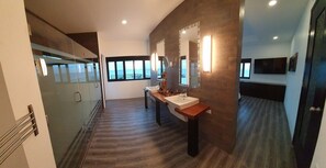 A modern bathroom with a large mirror, two sinks, and a view of the ocean through large windows.