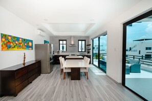 A modern kitchen with a dining area, large windows, and a view of the city.
