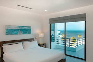 Enjoy ocean views from the balcony and relax in a spacious room with a large bed and a beautiful coastal painting above.